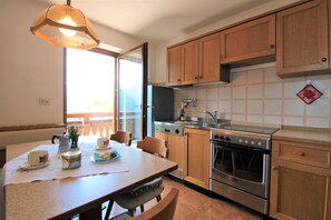 A kitchen with wooden cabinets, a stainless steel oven, and a dining table set with cups and plates.
