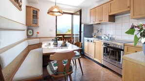 A kitchen with wooden cabinets, a stove, and a dining area with a bench and chairs.
