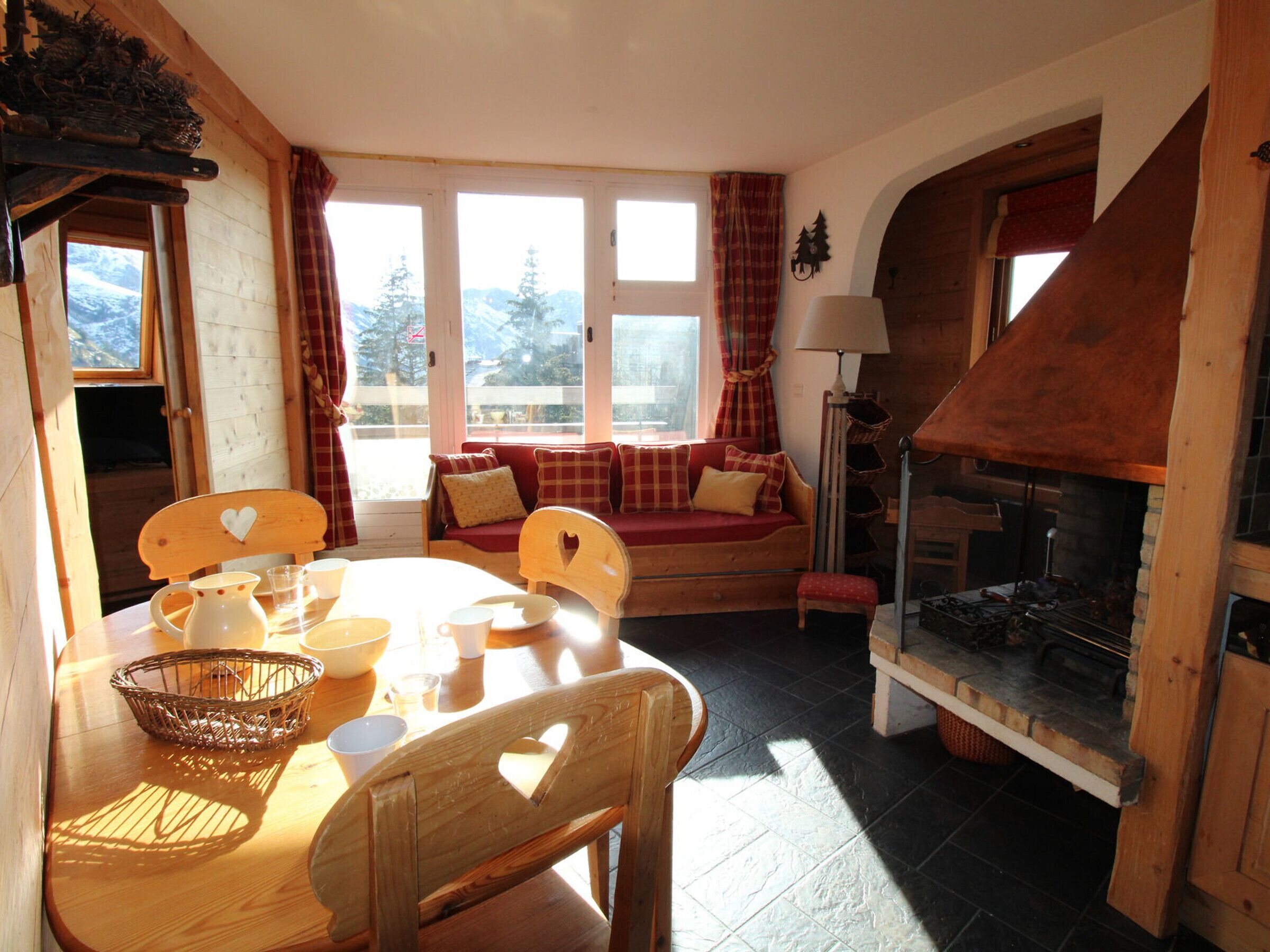A cozy room with a wooden table, chairs, a sofa, and a fireplace.