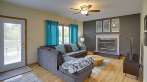 A living room with a gray sectional sofa, a fireplace, and a ceiling fan.