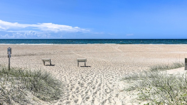 A beach with two empty chairs and a signpost. - Atlantic Beach Studio w/ Community Pool! (Atlantic Beach)