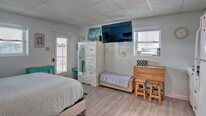 A bedroom with a bed, a dresser, a desk with two stools, a mirror, and a clock on the wall. - Atlantic Beach Studio w/ Community Pool! (Atlantic Beach)