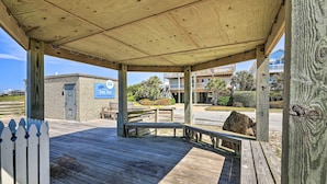 A wooden deck with a covered area, a small building with a sign, and a view of residential buildings in the background. - Atlantic Beach Studio w/ Community Pool! (Atlantic Beach)