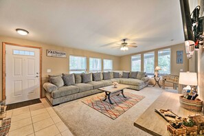 A spacious living room with a sectional sofa, a coffee table, and a ceiling fan.