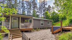 A two-story cabin with a front porch, a deck, and a hot tub.