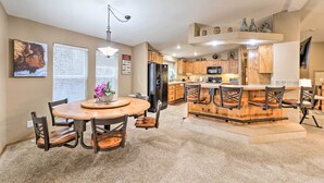 A spacious kitchen with wooden cabinets, a central island with bar stools, and a dining area with a round table and chairs.