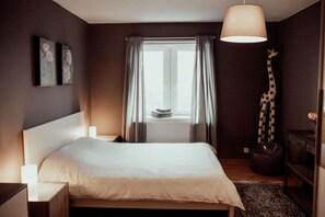 Un dormitorio con cama, ventana con cortinas, decoración de jirafa y una lámpara colgante.