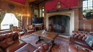 Un salón tradicional con chimenea, sofás de cuero, una mesa de centro de madera y un televisor.