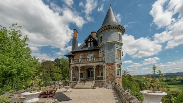 Una casa grande e histórica con una torre destacada y fachada de piedra.