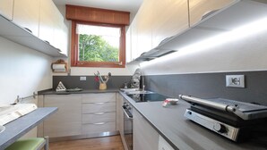 A compact kitchen with a window, stainless steel appliances, and a built-in oven.