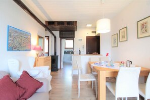 Une pièce comprenant un canapé, une table à manger avec des chaises, une lampe et des tableaux encadrés accrochés au mur.