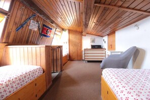 Een blokhut met twee houten bedden, een kitchenette en een houten plafond.