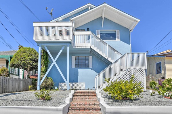 A two-story house with a blue exterior, a white balcony, and a brick staircase leading to the entrance. - Breezy Monterey Apt: Walk to Downtown & Beach (Monterey)
