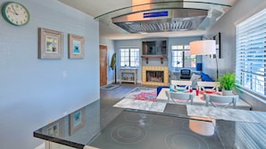 A modern kitchen with a glass cooktop, a stainless steel range hood, and a dining area with a fireplace. - Breezy Monterey Apt: Walk to Downtown & Beach (Monterey)