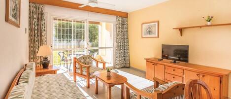 A living room with a sofa, chairs, a TV, and a wooden cabinet.