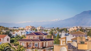 Un barrio residencial con casas, algunas con antenas parabólicas, y una cadena montañosa al fondo.
