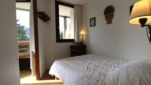 Ein Schlafzimmer mit Bett, Fenster, Nachttisch und Lampe.