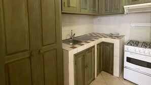 Una cocina con gabinetes verdes, una estufa blanca y un fregadero.