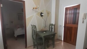 Un comedor con una mesa y sillas, una pared con diseños geométricos y una puerta con panel de madera.