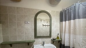 Un baño con lavamanos blanco, un espejo y cortina de ducha.