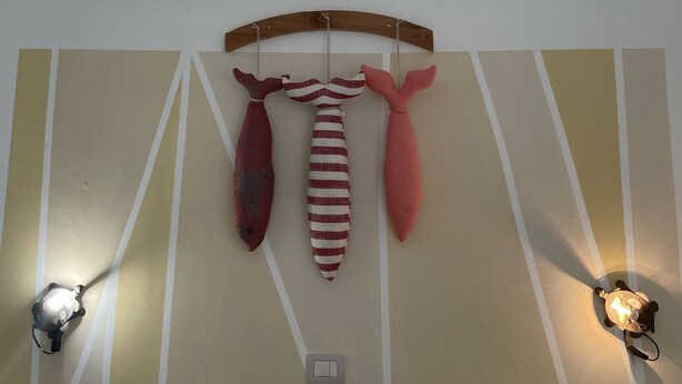 Una habitación con un muro decorativo, una lámpara colgante e iluminación en la pared.