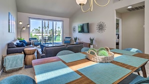 A modern living room with a large window, a dining area with a wooden table, and a seating arrangement including sofas and chairs. - Mtn & Golf Course Views: Relaxing Palm Desert Gem (Palm Desert)
