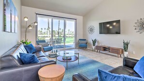 A modern living room with a leather sofa, a glass coffee table, and a TV mounted on the wall. - Mtn & Golf Course Views: Relaxing Palm Desert Gem (Palm Desert)