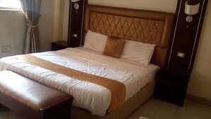 A neatly made bed with a wooden headboard, a bench at the foot of the bed, and bedside tables on either side. - Mesfin Harar Hotel (Addis Ababa)