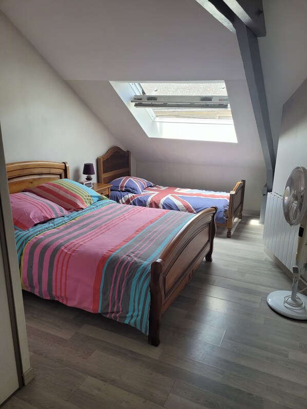 A bedroom with two wooden beds, a skylight, a standing fan, and a radiator. - Duplex apartment in the heart of La Roche Bernard (La Roche-Bernard)