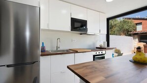 Eine moderne Küche mit weißen Schränken, einem Edelstahl-Kühlschrank, einer Mikrowelle und einer Holz Arbeitsplatte.