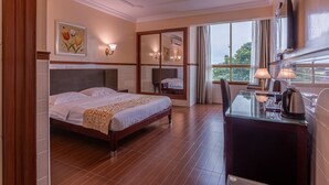 A hotel room with a bed, a desk with a kettle, a TV, and a large window with a view. - L'Etoile d'Or Hotel London (Libreville)