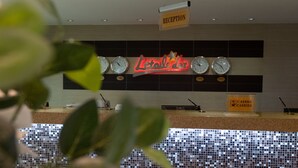 A reception area with a neon sign, clocks, and a cash register. - L'Etoile d'Or Hotel London (Libreville)