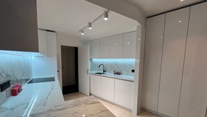 A modern kitchen with white cabinets, a marble countertop, and a sink.