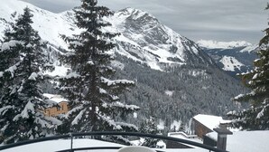A snow-covered mountain landscape with a view of a building and trees.