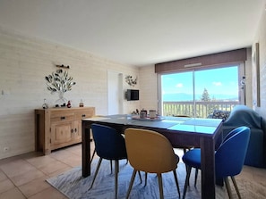 A dining area with a table, chairs, a wooden cabinet, and a TV on the wall.