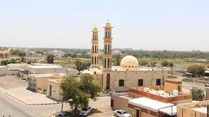 A mosque with two minarets and a dome, surrounded by residential buildings and a clear sky. - MARINA SOHAR HOTEL (Sohar)