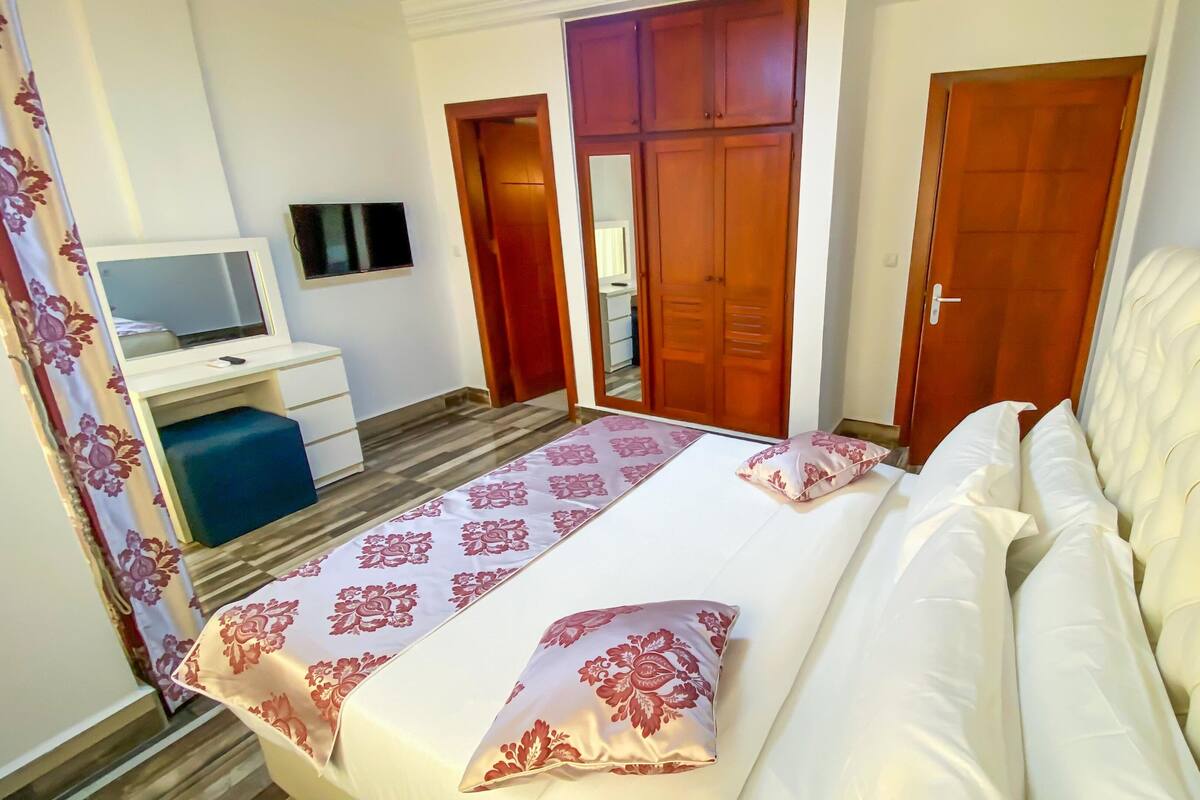A hotel room with a bed, a desk with a TV, and a wardrobe.