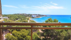 A coastal view from a balcony with a clear sky, a beach, and buildings in the distance. - AirCon Apartment · Sea Views  · Pool · UHC CALA DORADA (Salou)