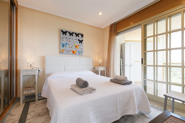 A hotel room with a large bed, two bedside tables with lamps, a window with curtains, and a butterfly wall art piece.