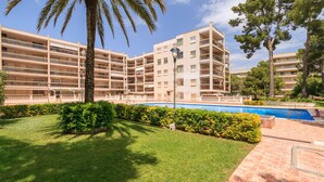 A multi-story residential building with balconies, a swimming pool, and well-maintained lawns. - AirCon Apartment · Sea Views  · Pool · UHC CALA DORADA (Salou)
