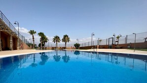 Uma piscina azul clara, com uma parede de pedra de um lado e uma cerca do outro.