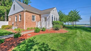 A two-story brick house with a white porch, a well-maintained lawn, and a clear view of the sky.