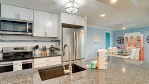 Una cocina moderna con electrodomésticos de acero inoxidable, encimera de granito y comedor con una pared de acento azul.