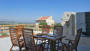 A wooden table with chairs on a terrace overlooking a cityscape. - Arismari Villa - Private Pool (Hersonissos)