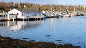 A waterfront seafood restaurant with a dock extending into calm water, surrounded by boats and trees. - Pinot (Ryde)
