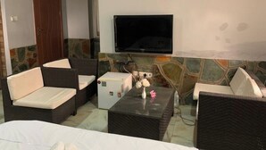 Ein Zimmer mit einem Bett, zwei Sofas, einem Couchtisch, einem Fernseher und einer Steinwand.