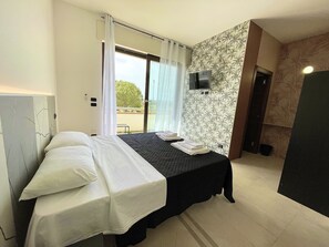 Une chambre d’hôtel avec un lit, une télévision, un balcon avec vue et une porte.