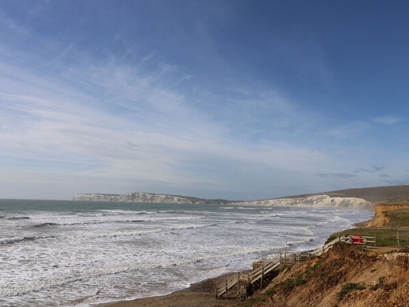 A coastal landscape with cliffs and a wooden walkway leading to the beach. - Amarone (Ryde)