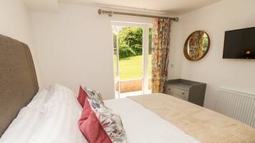 A bedroom with a bed, a dresser, a television, and a window with curtains.