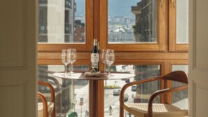 Uma área de jantar com uma mesa posta para dois, uma garrafa de vinho e duas cadeiras.